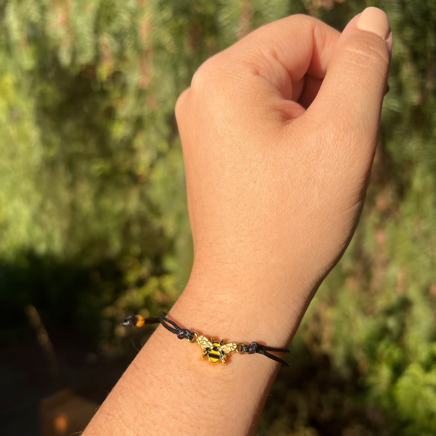 Hand wearing a bracelet with a blurred green background