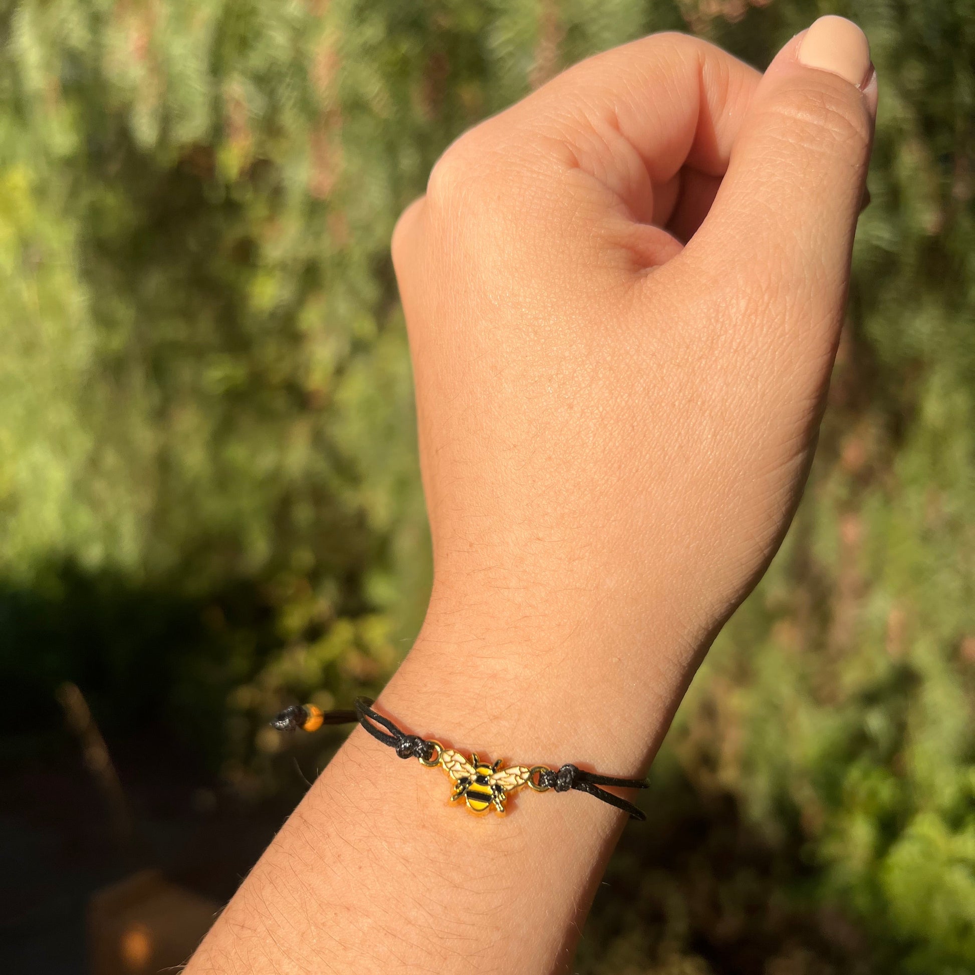 Hand wearing a bracelet with a blurred green background