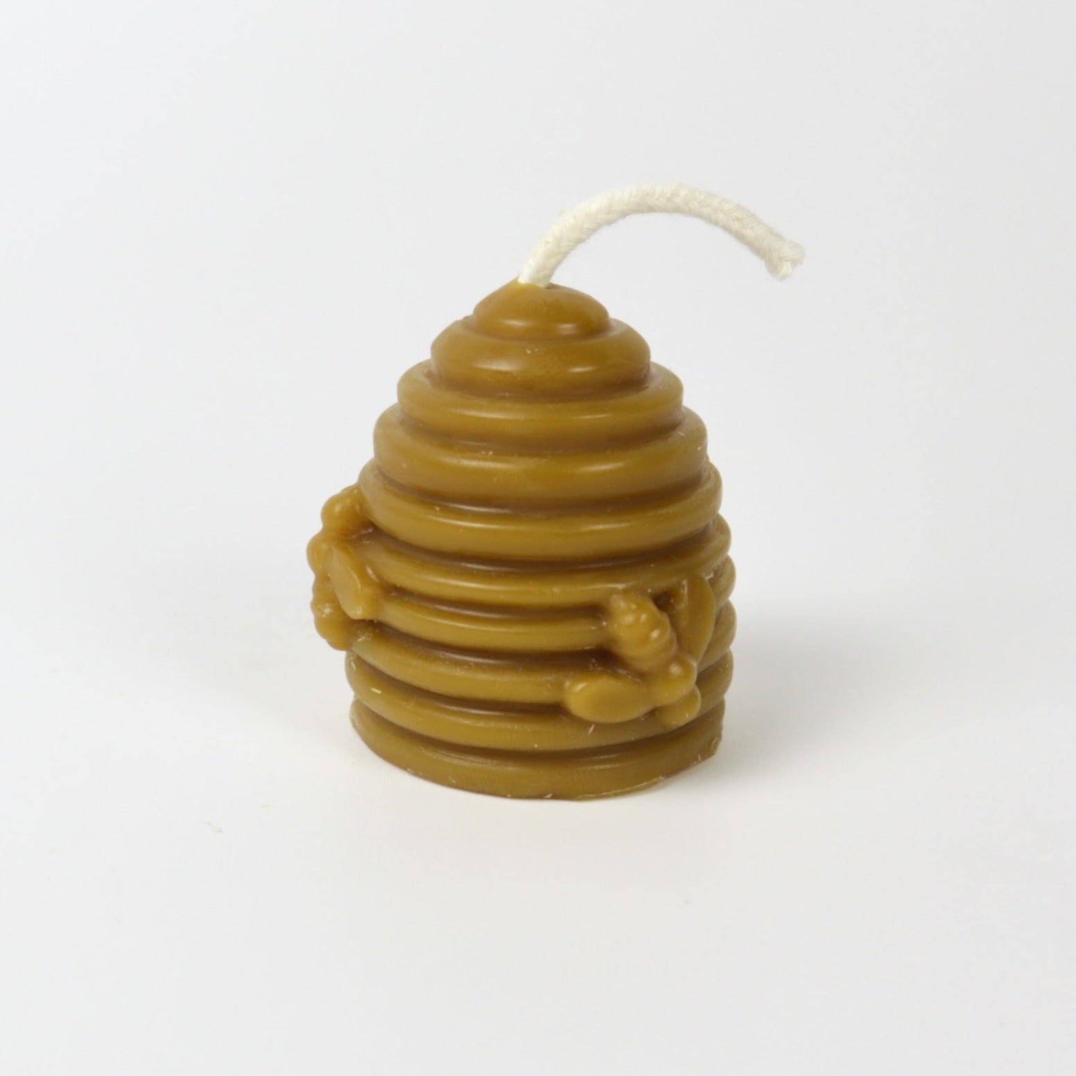 Beeswax candle shaped like a beehive on a white background